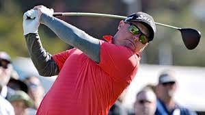 Ted Potter after swing with mirrored glasses, black hat and red shirt